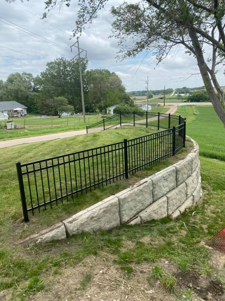 Black ornamental fence installed above a retaining wall