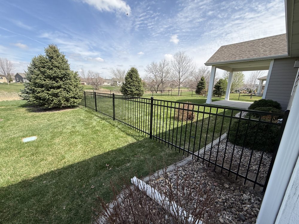 Black ornamental fence installed beside a covered patio