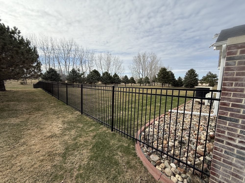 Ornamental iron fence installed along a stone border