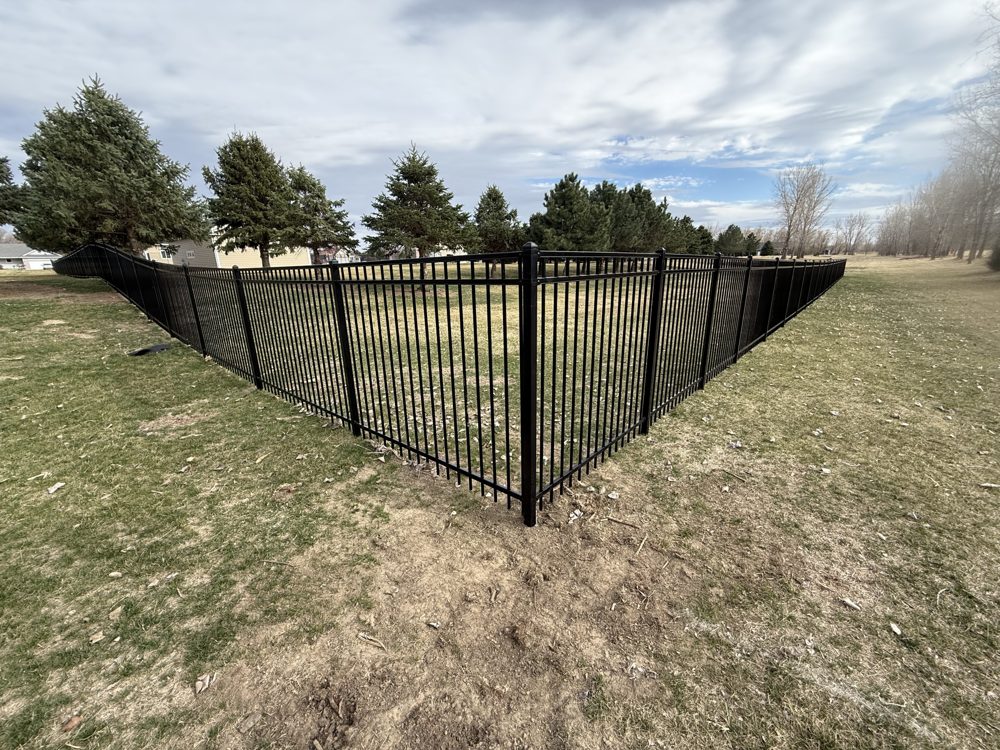 Black ornamental fence installed along an open field line