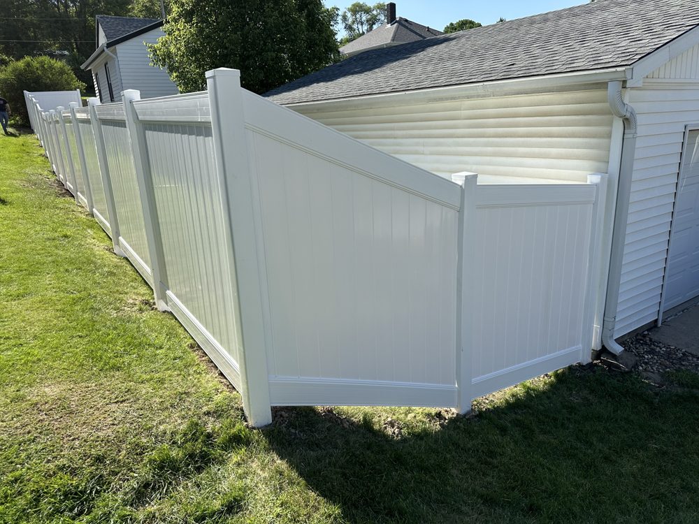 White vinyl privacy fence installed along a home