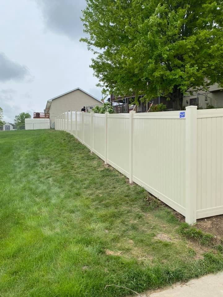 White vinyl privacy fence installed along a sloped yard