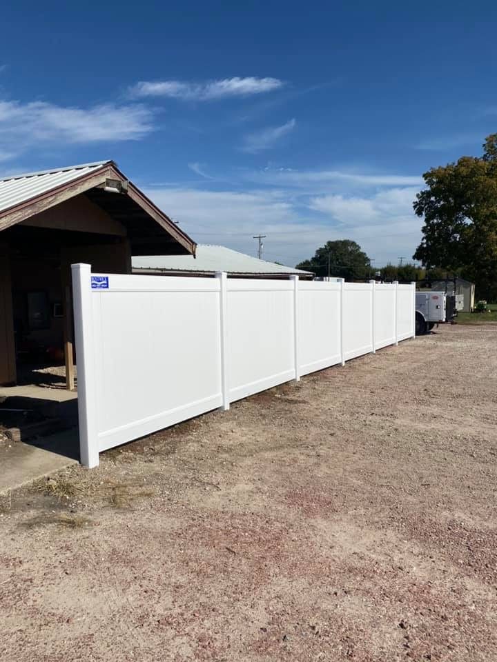 White vinyl fence installed beside a shop building